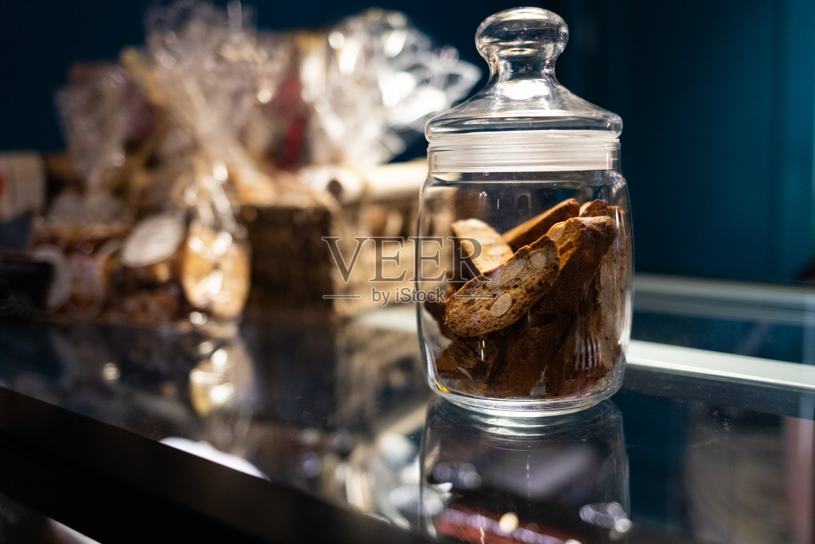 一个装有甜脆饼干的玻璃罐放在咖啡馆的展示柜上。照片摄影图片
