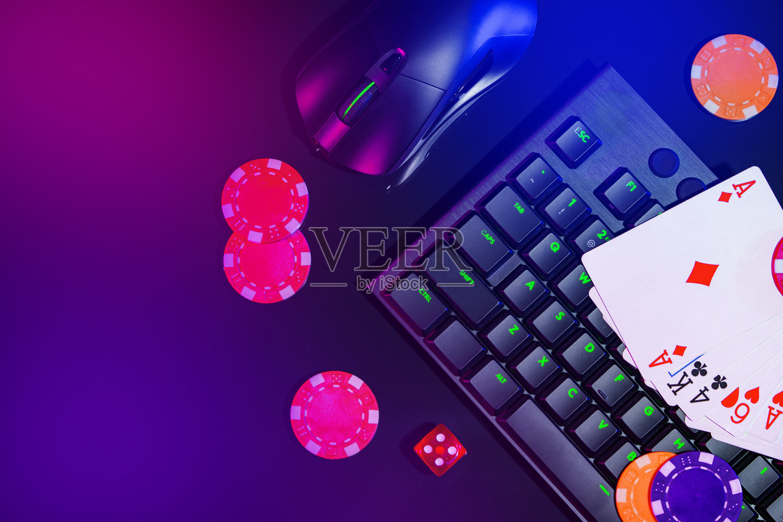 在晚上的在线赌场设置中,色彩斑斓的扑克筹码和扑克牌摆放在游戏键盘上,旁边有一只鼠标。照片摄影图片