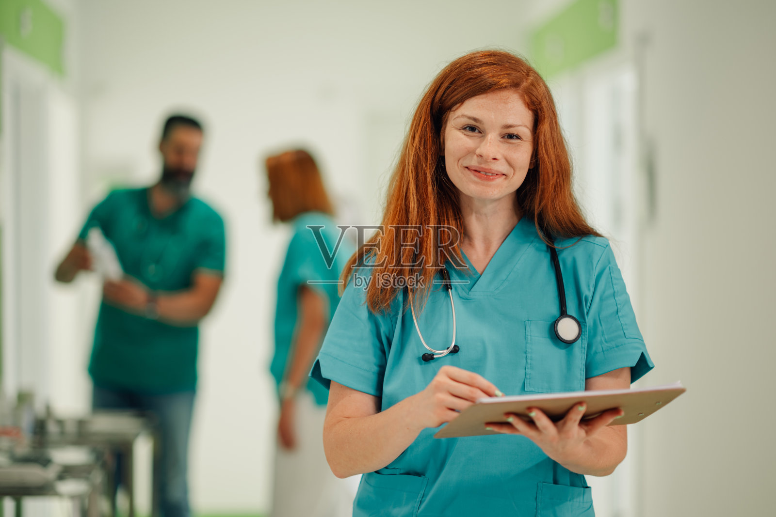 在医院走廊中自信微笑的护士手持夹板照片摄影图片