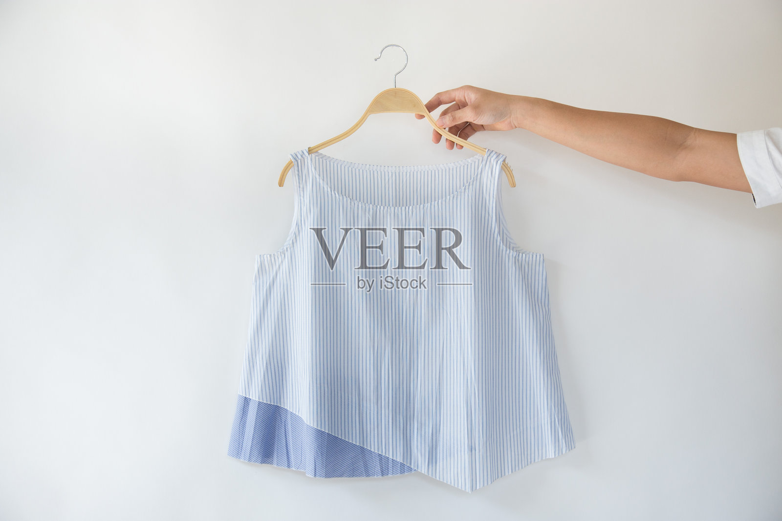 女人的手握着挂在墙上的上衣照片摄影图片