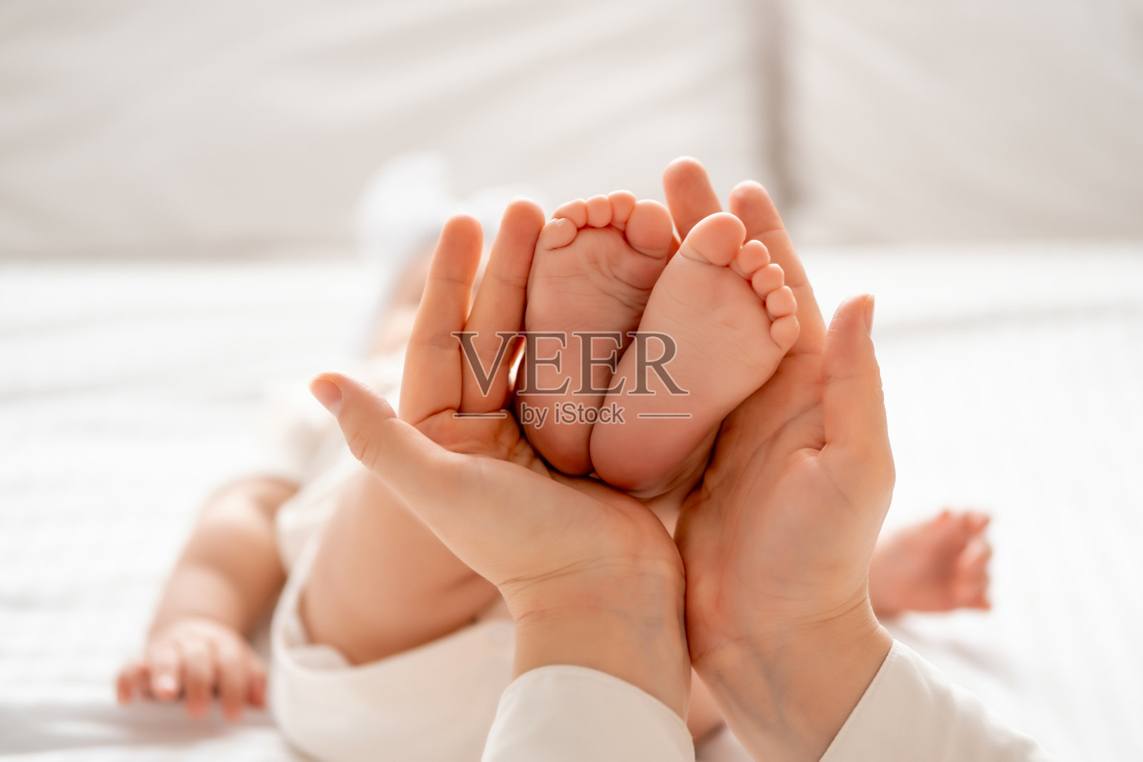 妈妈的手握着小孩的腿,背景为白色。照片摄影图片