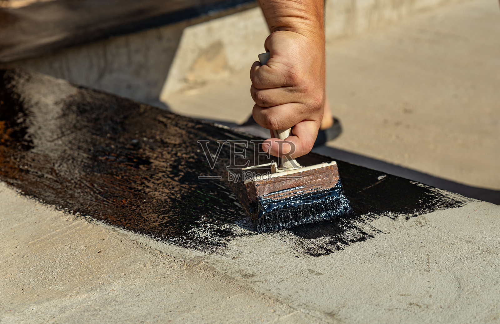 防水地下室和基础的施工技术。地下室混凝土墙上的绝缘材料。使用喷涂沥青和卷材防水材料进行房屋基础防水。照片摄影图片