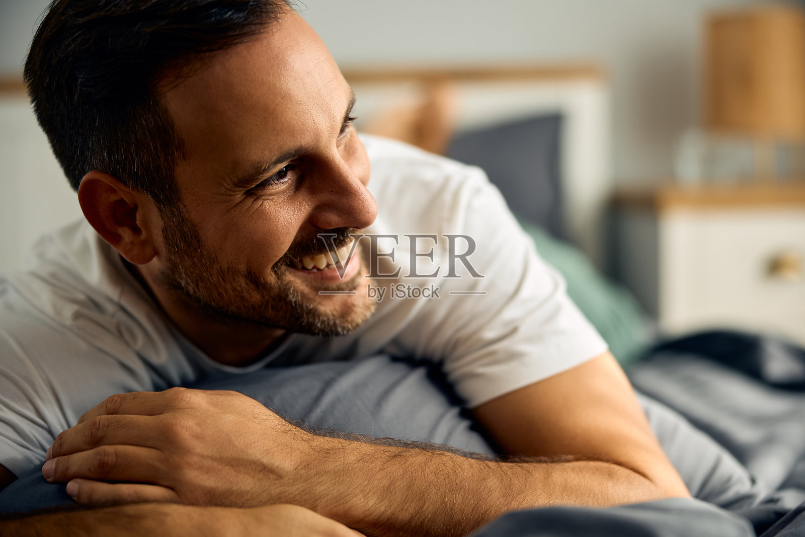 快乐的男人在卧室里放松。照片摄影图片