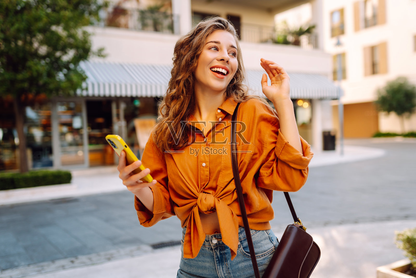 快乐的年轻女性卷发在户外城市中享受阳光明媚的一天。照片摄影图片