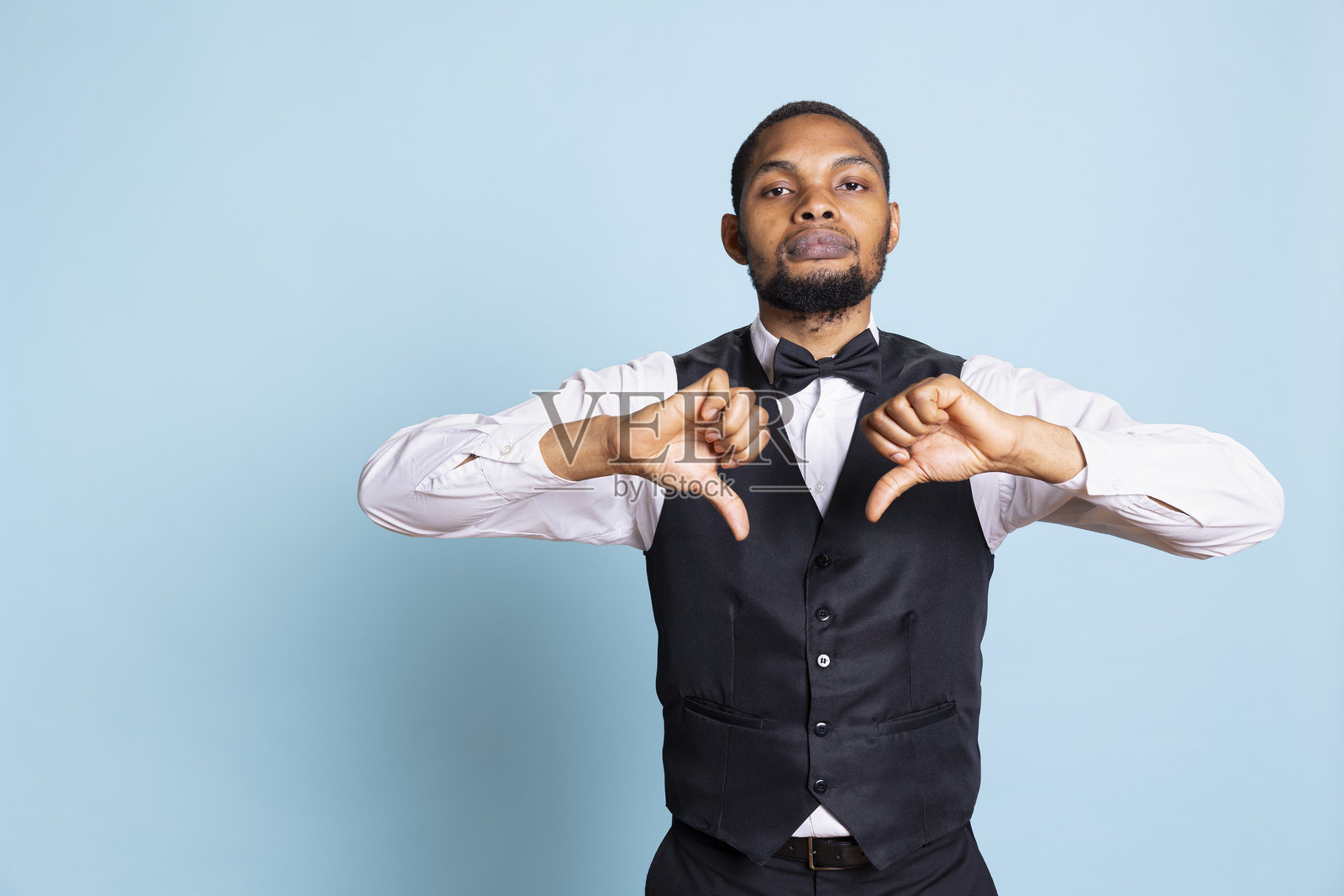 不满的酒店侍者对着镜头竖起了一个倒拇指的手势照片摄影图片