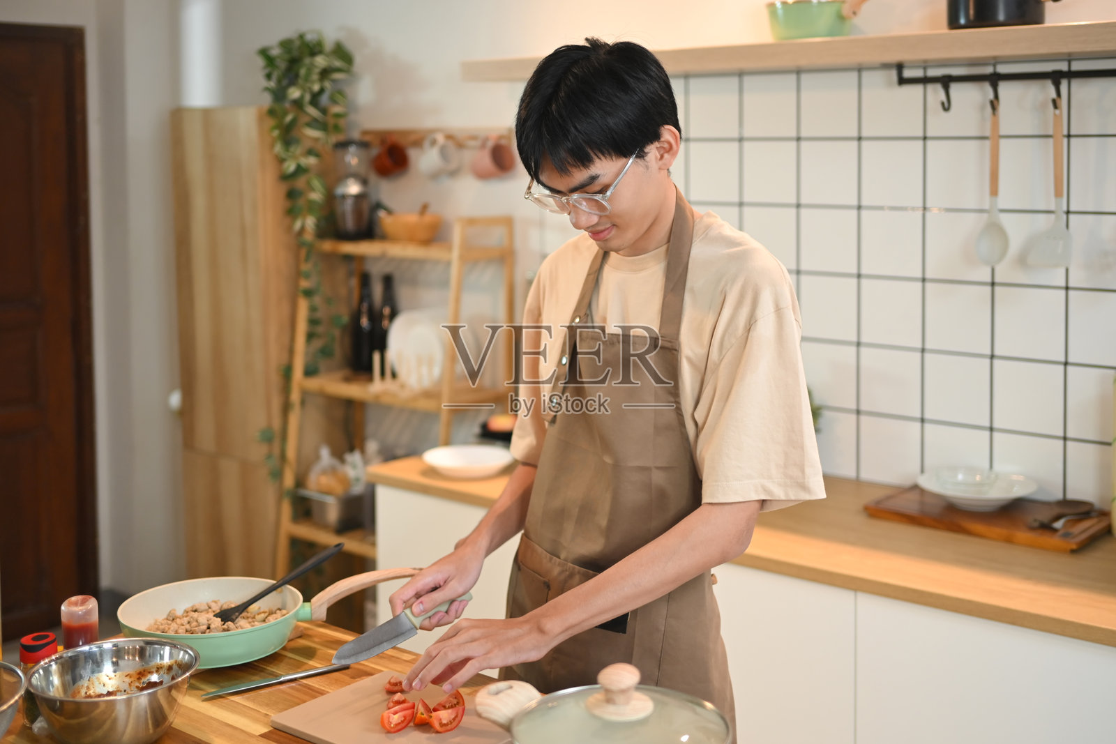 年轻的亚洲男子穿着围裙在家中的厨房准备健康食品照片摄影图片