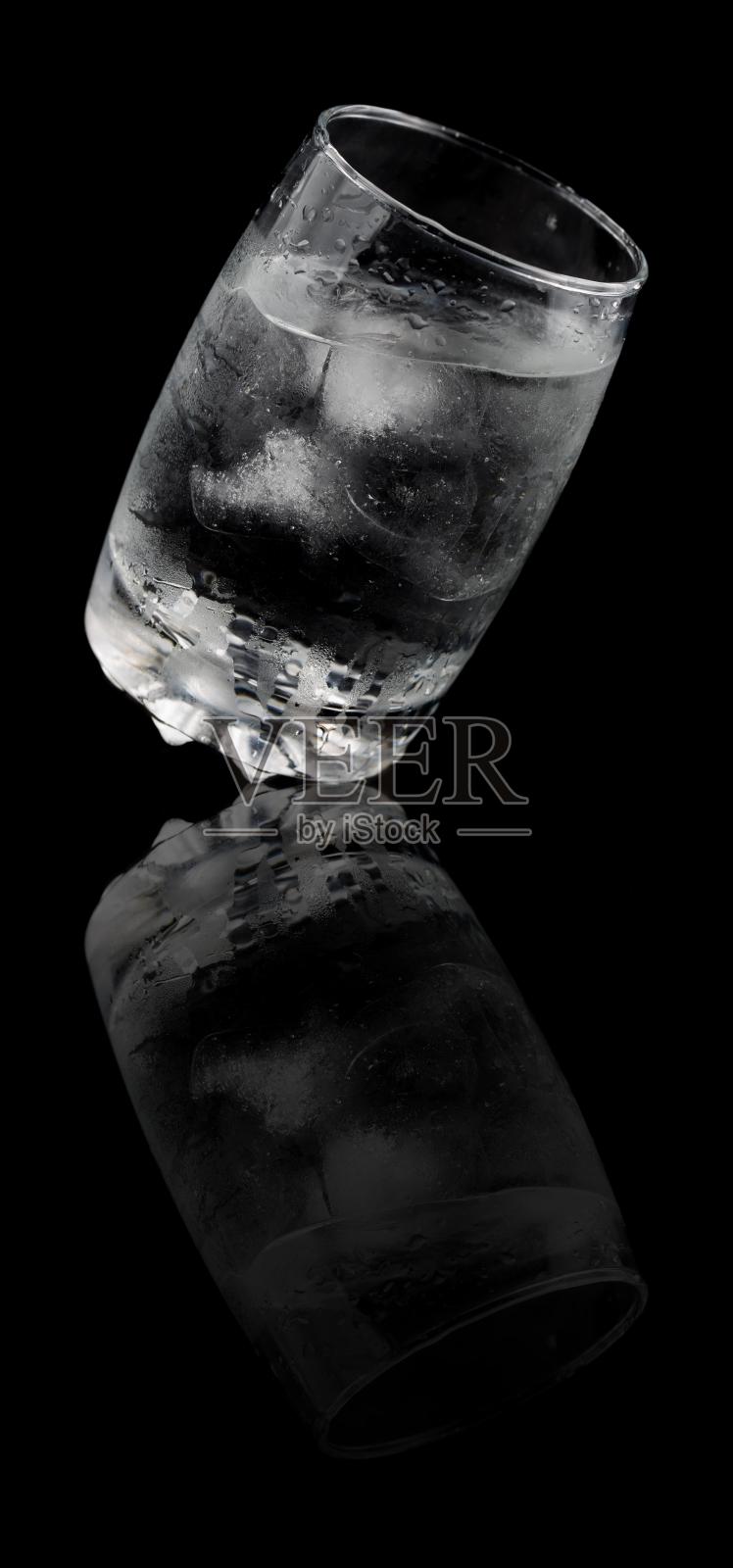 黑色背景上的透明玻璃杯,里面装有冰块和水照片摄影图片