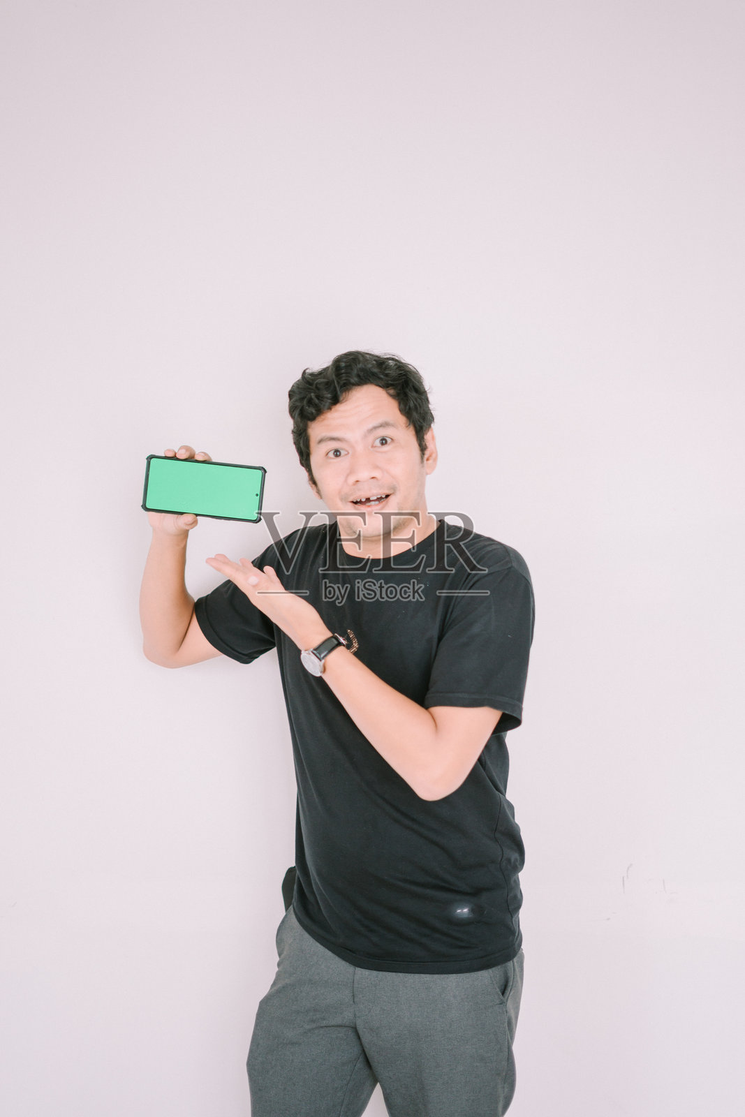 一名男子手持绿幕手机,指向镜头。照片摄影图片