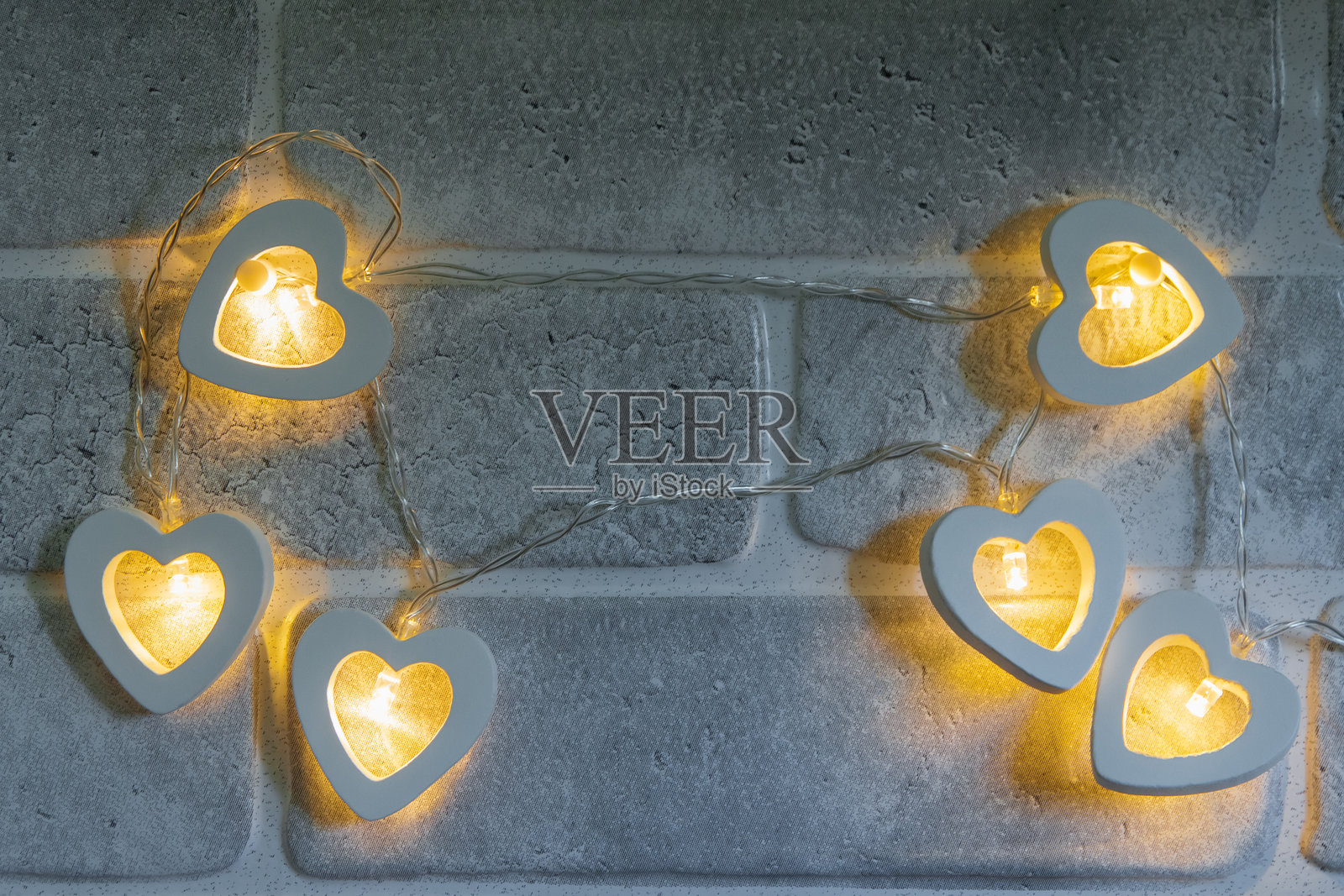 石墙背景上的心形黄色灯串照片摄影图片