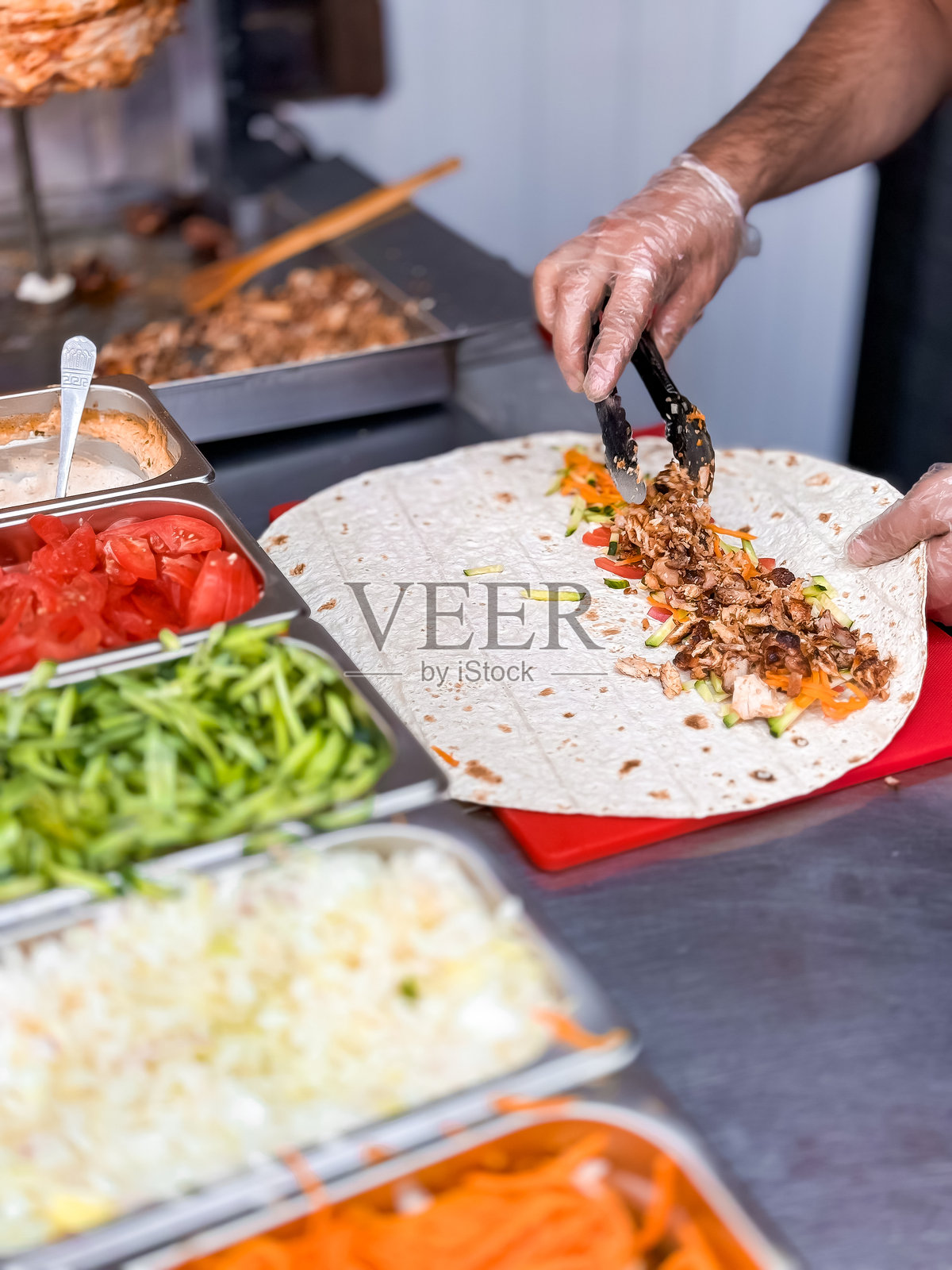 厨师在厨房中准备新鲜的沙威玛卷,搭配色彩鲜艳的蔬菜照片摄影图片