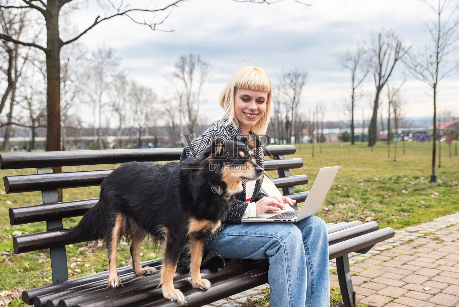年轻女性宠物主人和她的收养救助犬在户外散步,享受彼此的友谊。时尚的女性展现出酷酷的态度,代表着年轻文化和收养被遗弃动物的理念。照片摄影图片