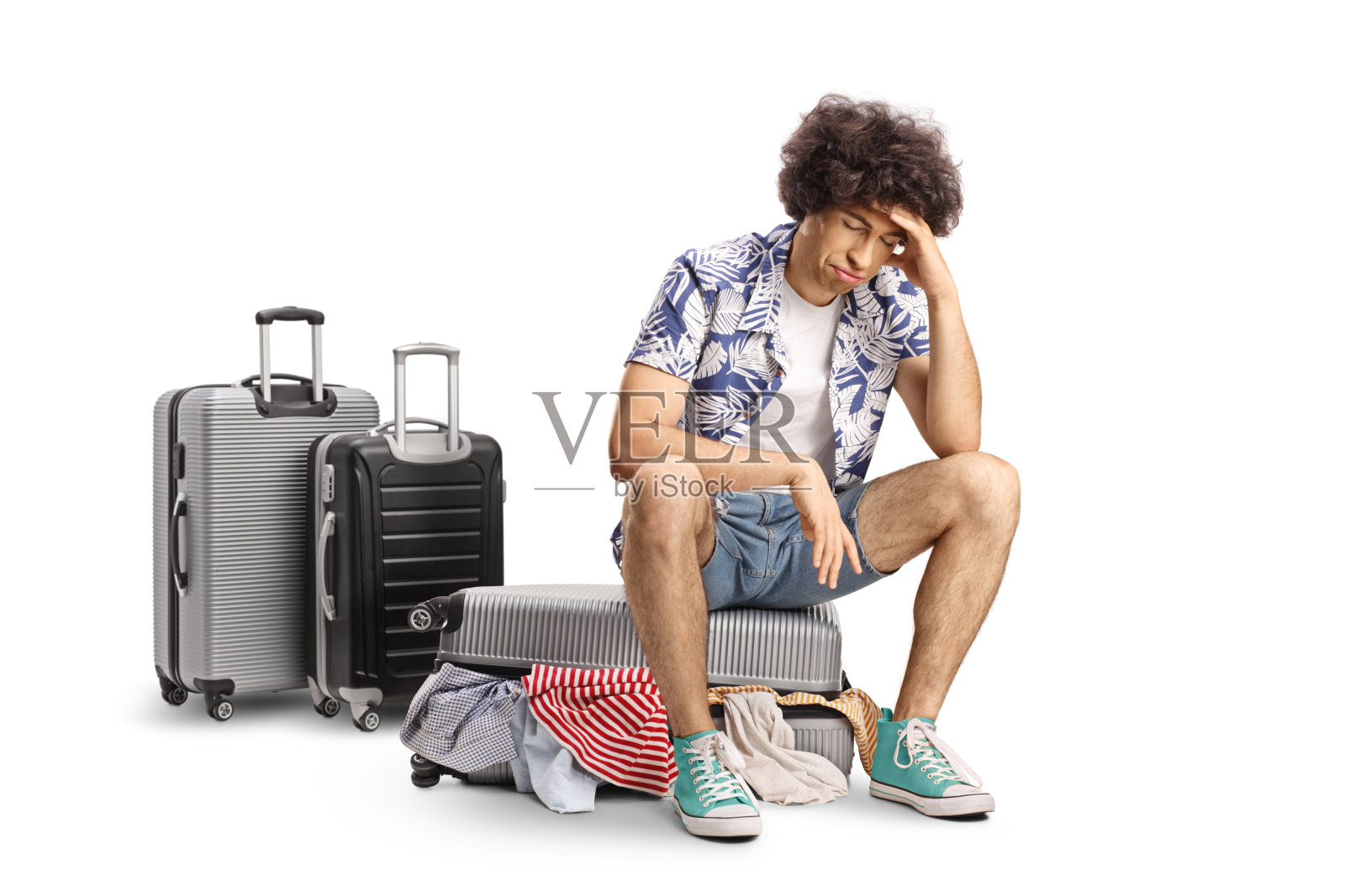 伤心的年轻人坐在装满行李的行李箱上照片摄影图片