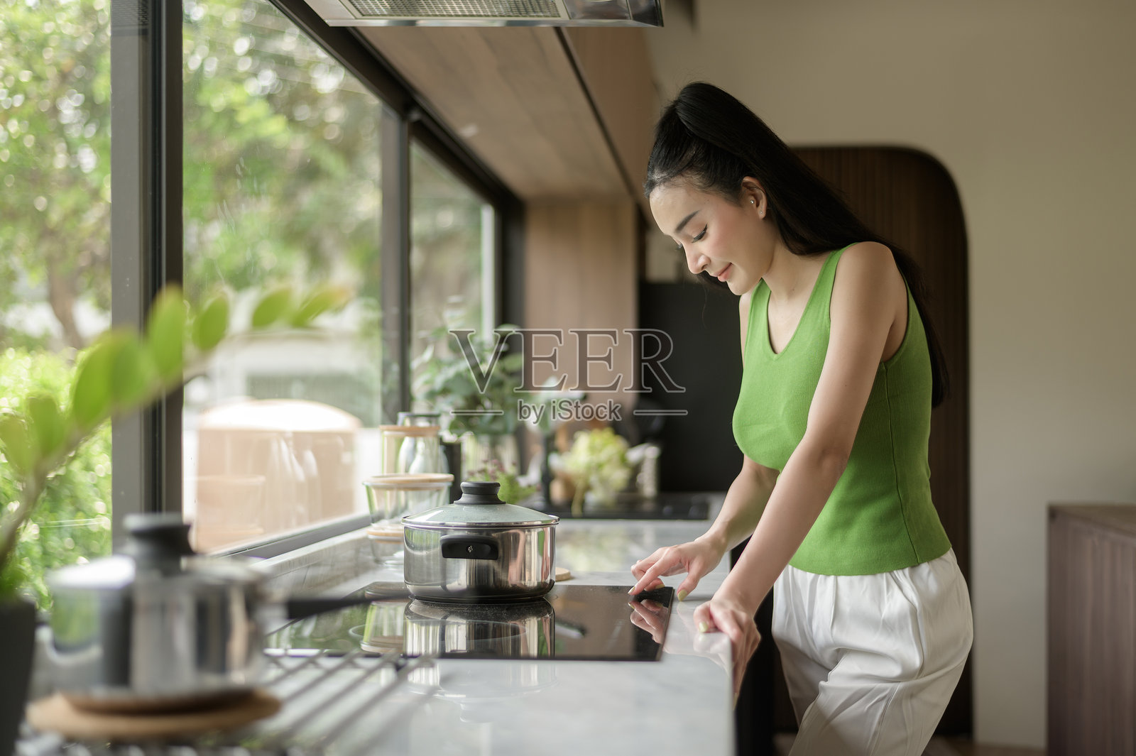 亚洲女性在家中的厨房桌子上烹饪并品尝锅里的汤。照片摄影图片