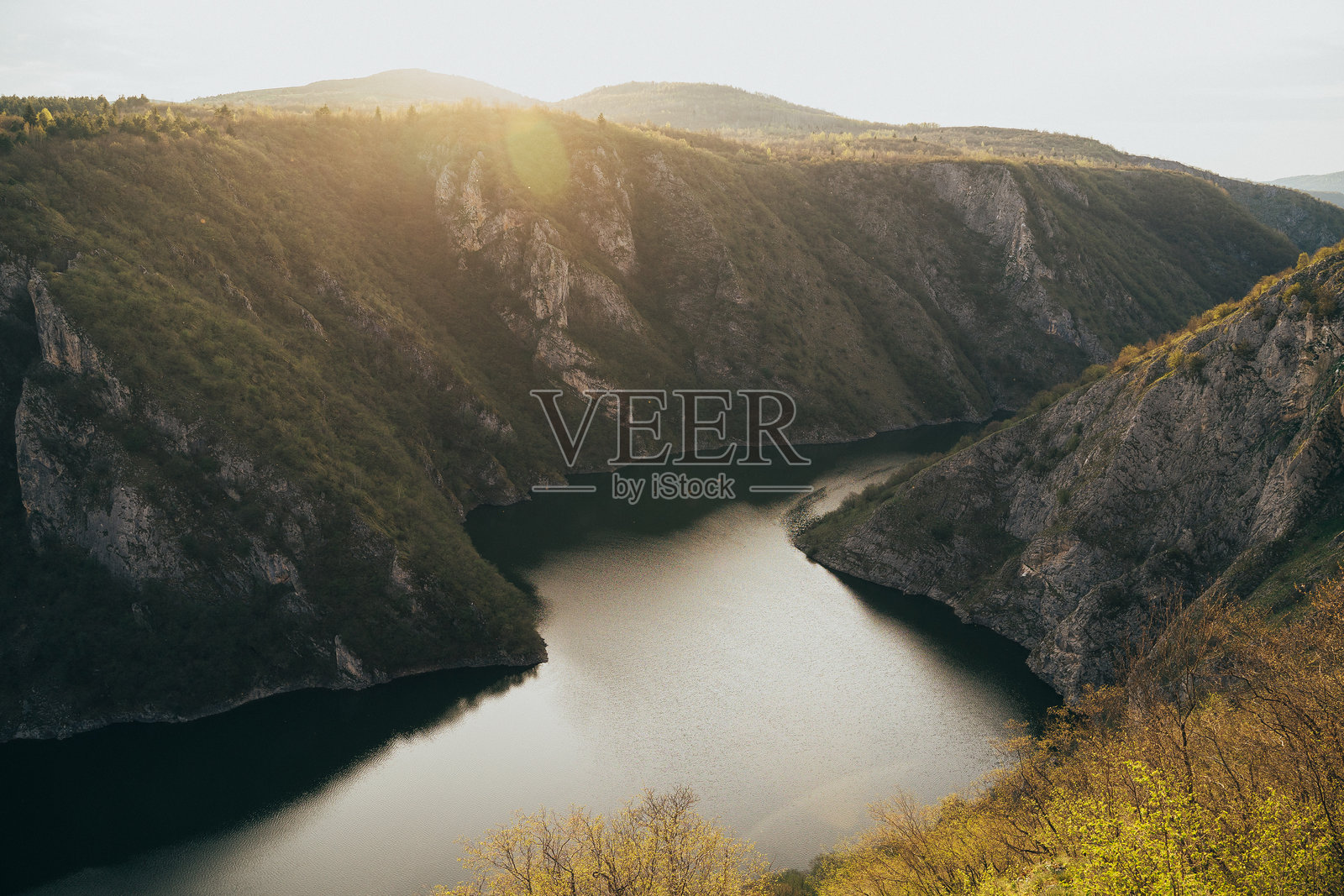塞尔维亚初春时节,壮观的日落映照在宁静的河谷上,四周被崎岖的山崖环绕。照片摄影图片