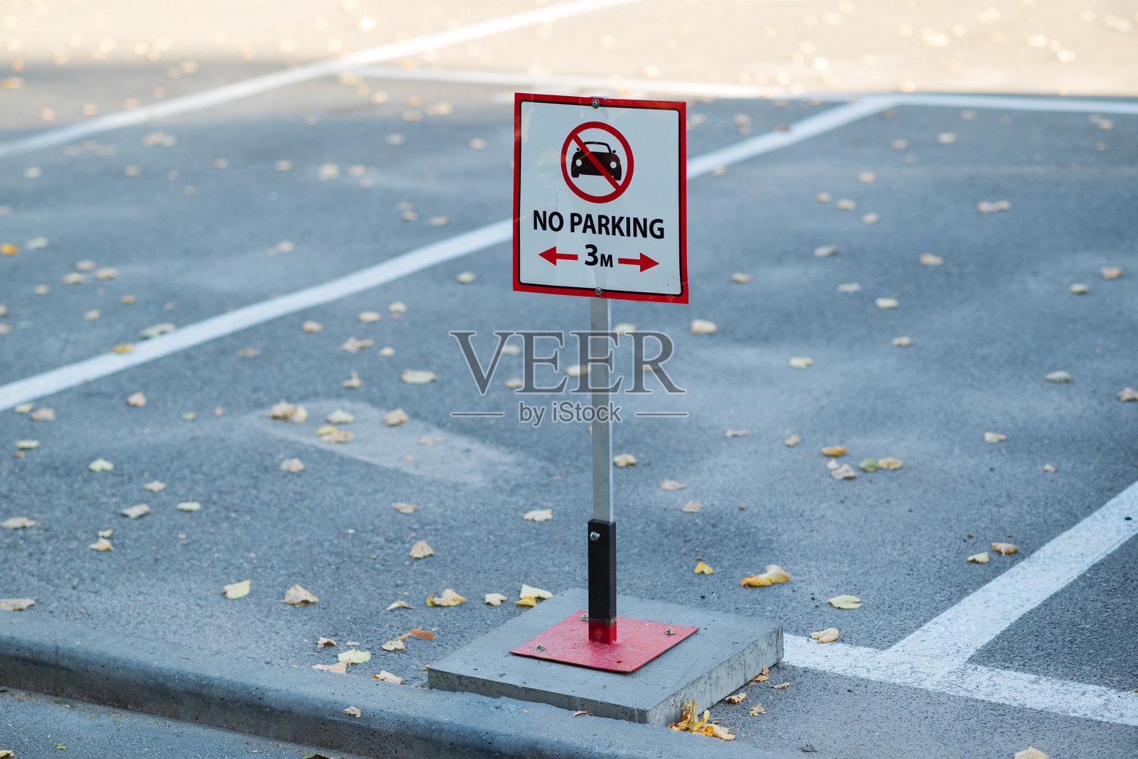 空旷停车场中的“禁止停车”标志。地面上部分覆盖着落叶。照片摄影图片