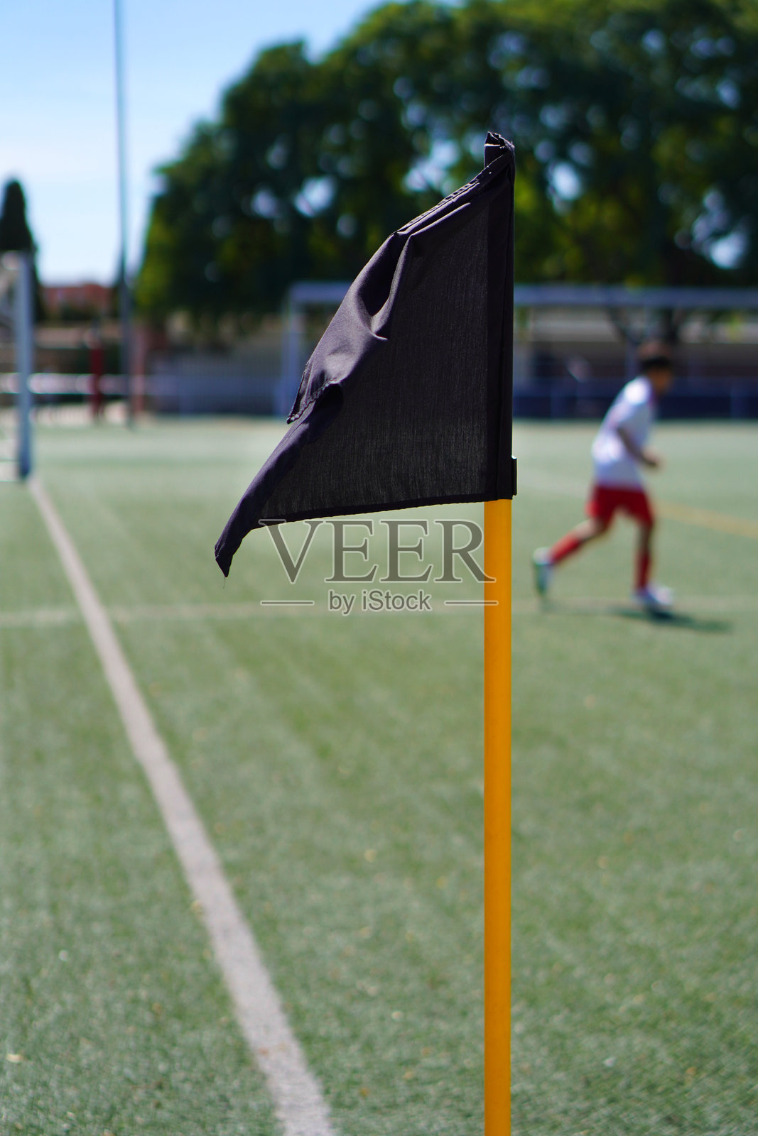 足球场的角旗,背景中模糊的人们正在踢球照片摄影图片
