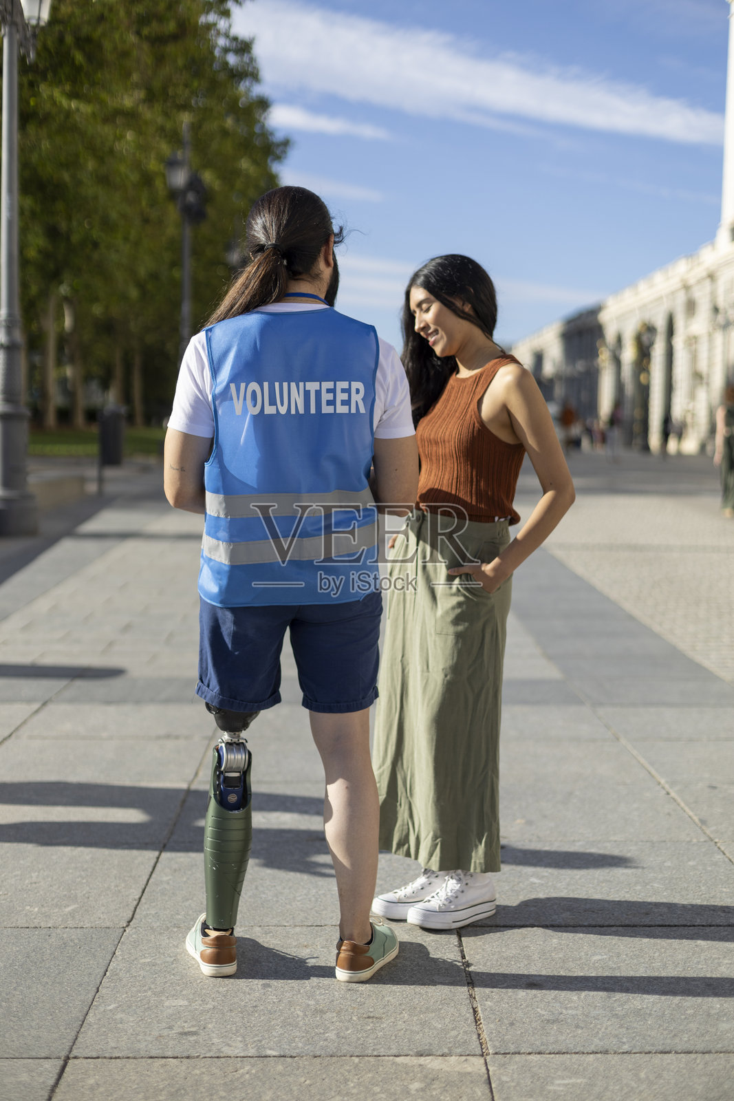 装有假肢的年轻志愿者与街头妇女交谈照片摄影图片