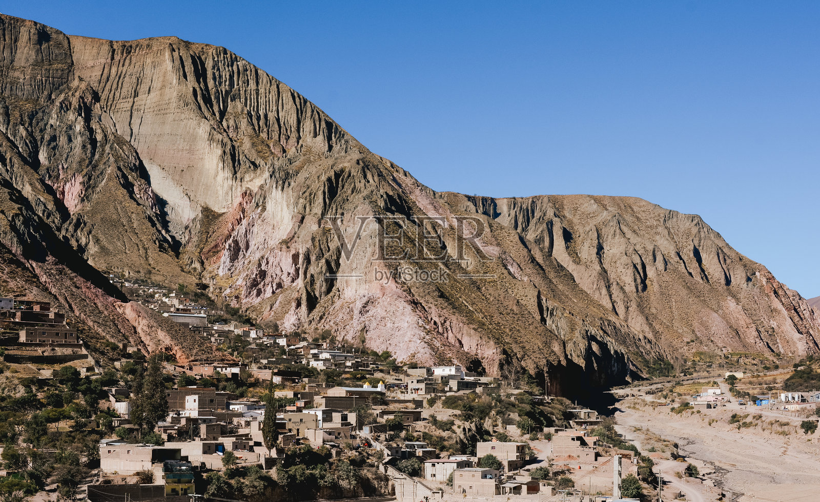 美丽的全景视图,展示了阿根廷北部一个小型殖民地和土著城镇伊鲁亚,背景是美丽的山脉和土坯房屋。照片摄影图片