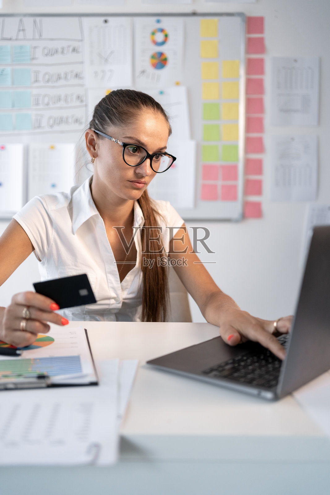 戴眼镜的年轻女性正在用信用卡在线购物照片摄影图片