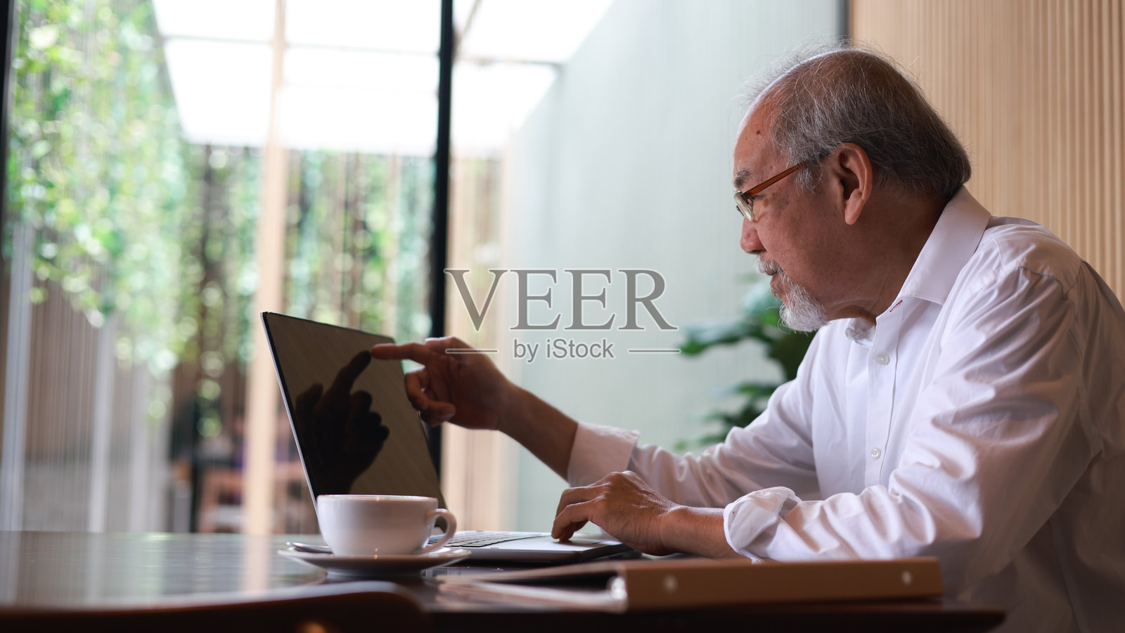 年长的商务人士在舒适的咖啡馆里阅读和使用笔记本电脑照片摄影图片