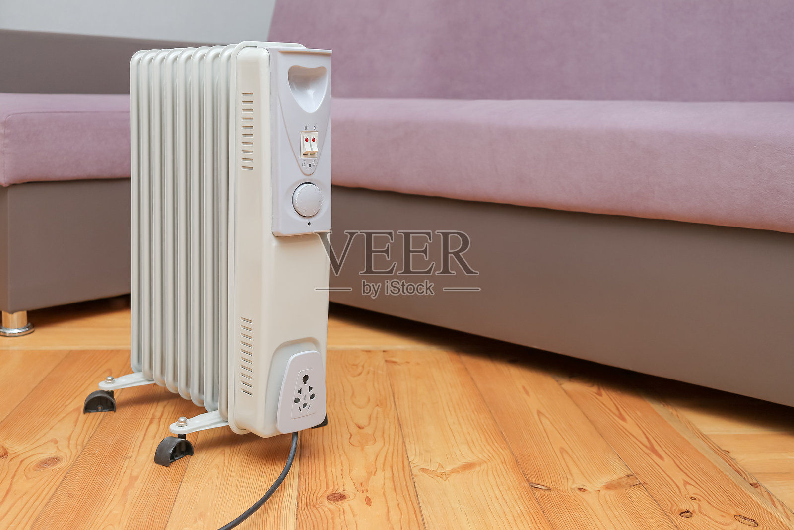油汀取暖器,沙发旁的地面上,无人空房间,采暖季概念照片摄影图片