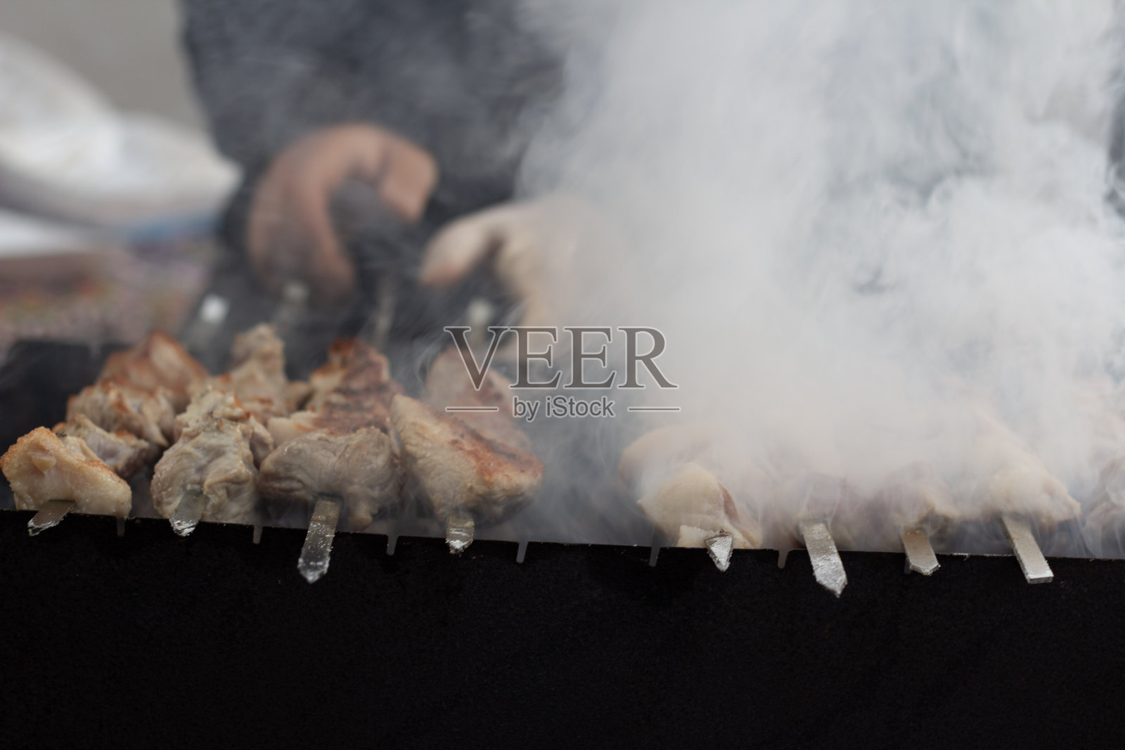 厨师在城市集会上烤制串烧。烟雾缭绕。照片摄影图片