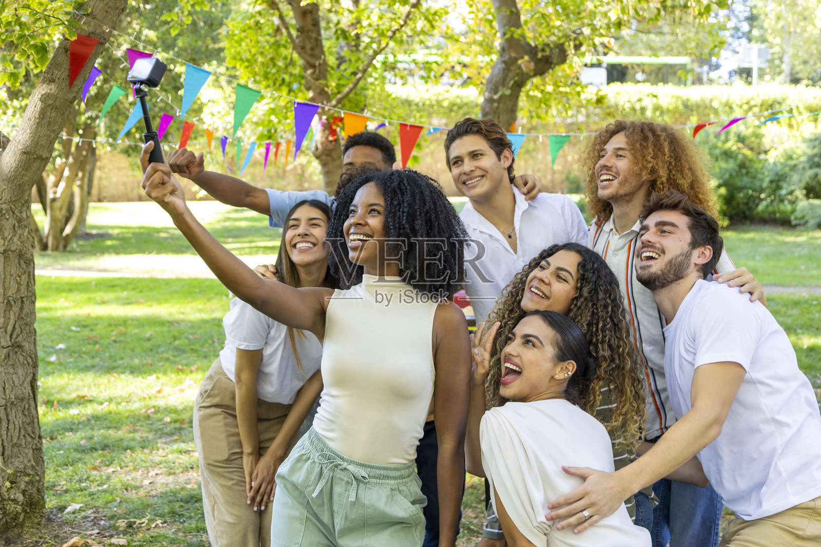 一群朋友用自拍杆自拍,在户外聚会上微笑照片摄影图片