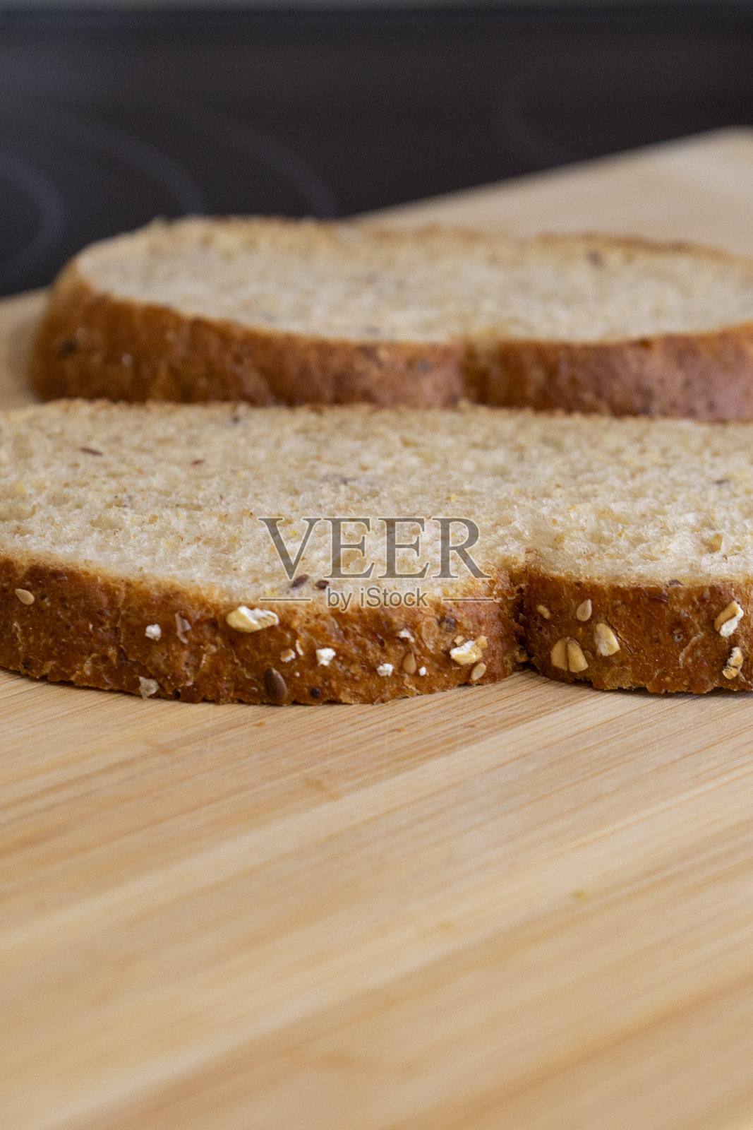 切片面包上撒有芝麻,放在木砧板上照片摄影图片