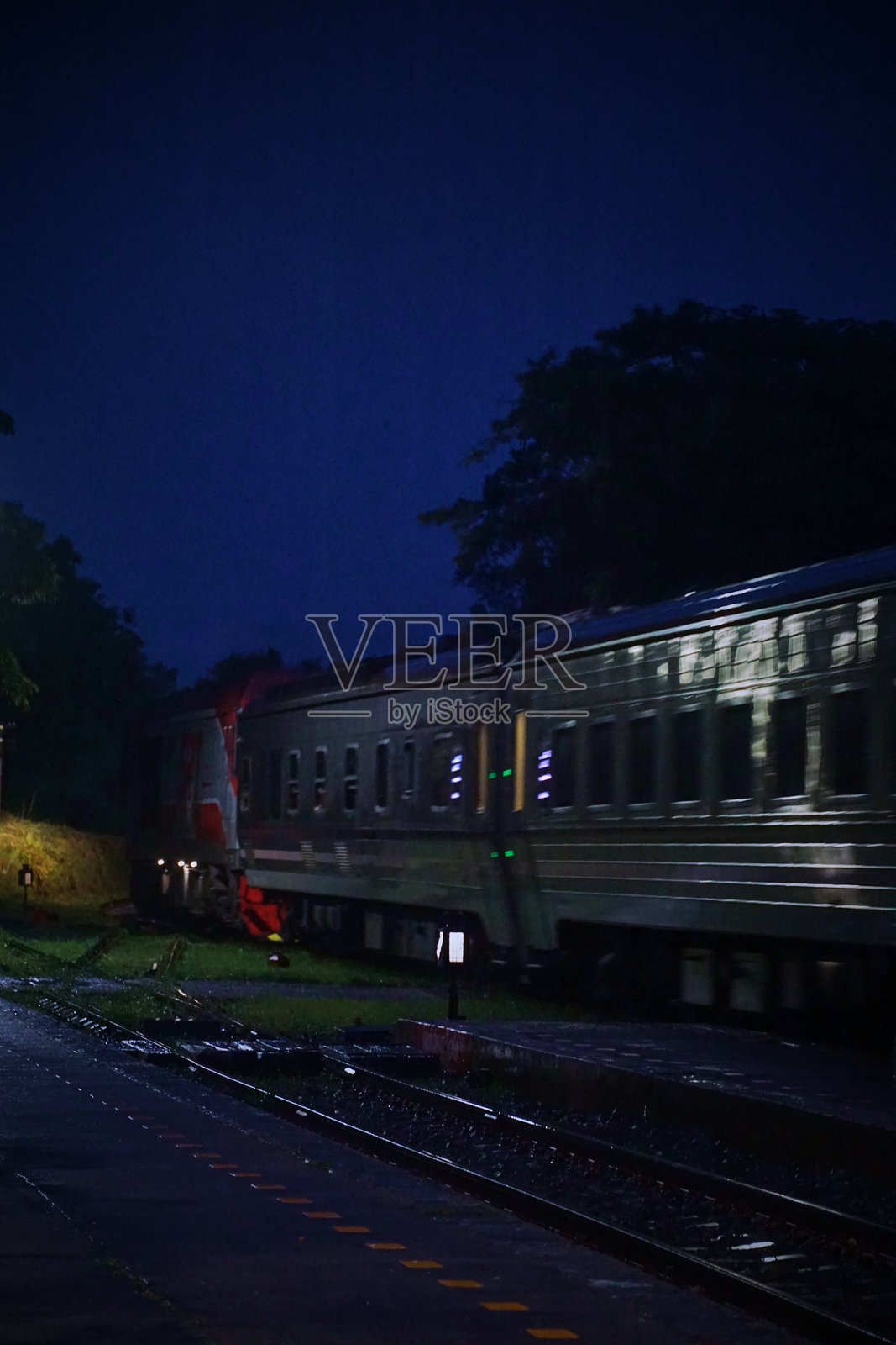 夜间,一列火车在轨道上行驶。照片摄影图片