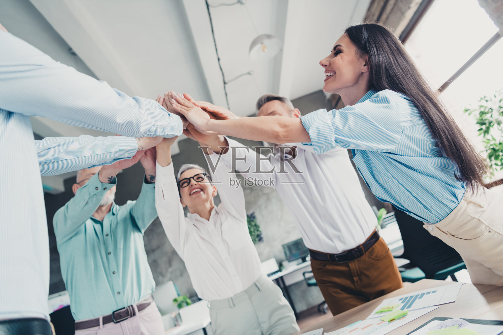 创业团队在舒适的loft办公室中手牵手合影照片摄影图片