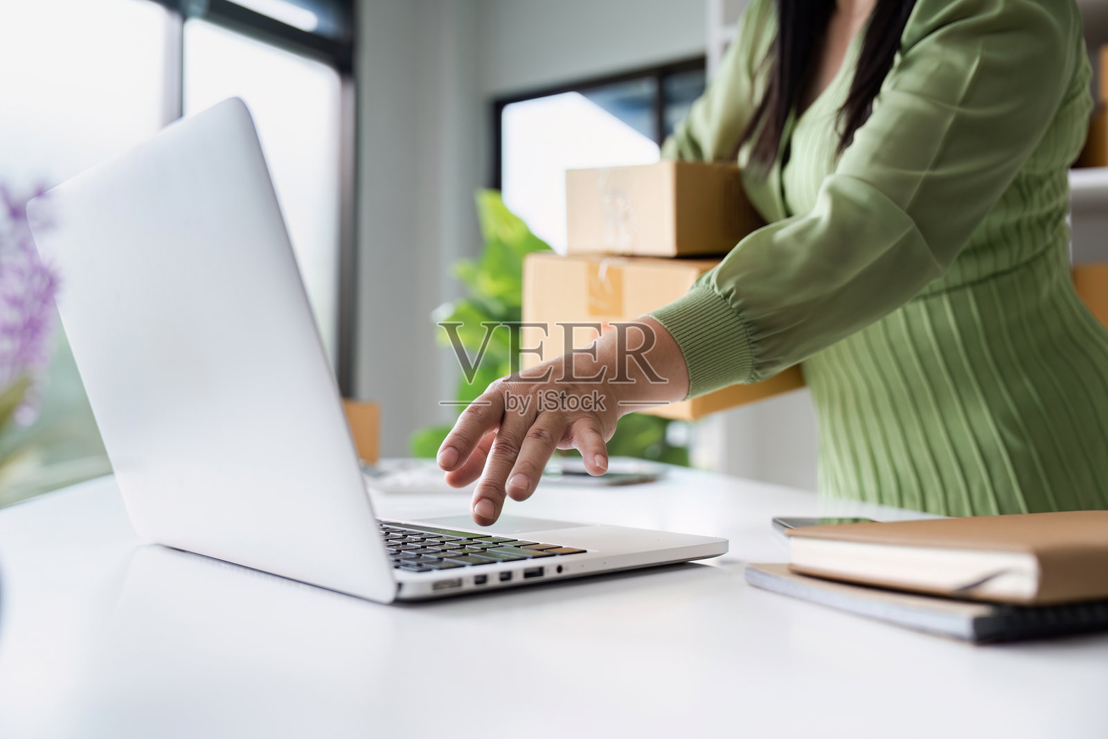 小企业主在现代办公室使用笔记本电脑和包装盒管理在线订单照片摄影图片