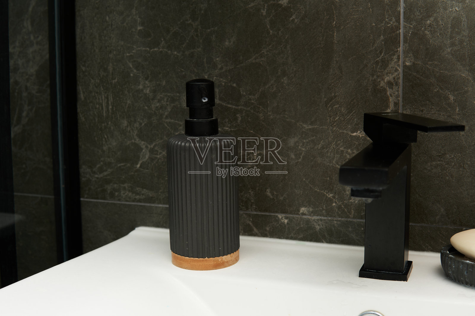 一款光滑黑色的肥皂分配器,带有纹理表面和木质底座照片摄影图片