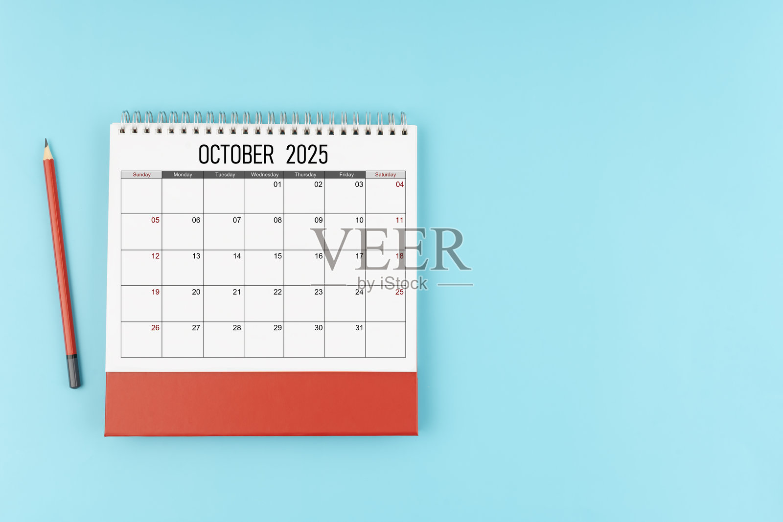 2025年十月桌面日历与铅笔,蓝色背景,留有空白位置。照片摄影图片