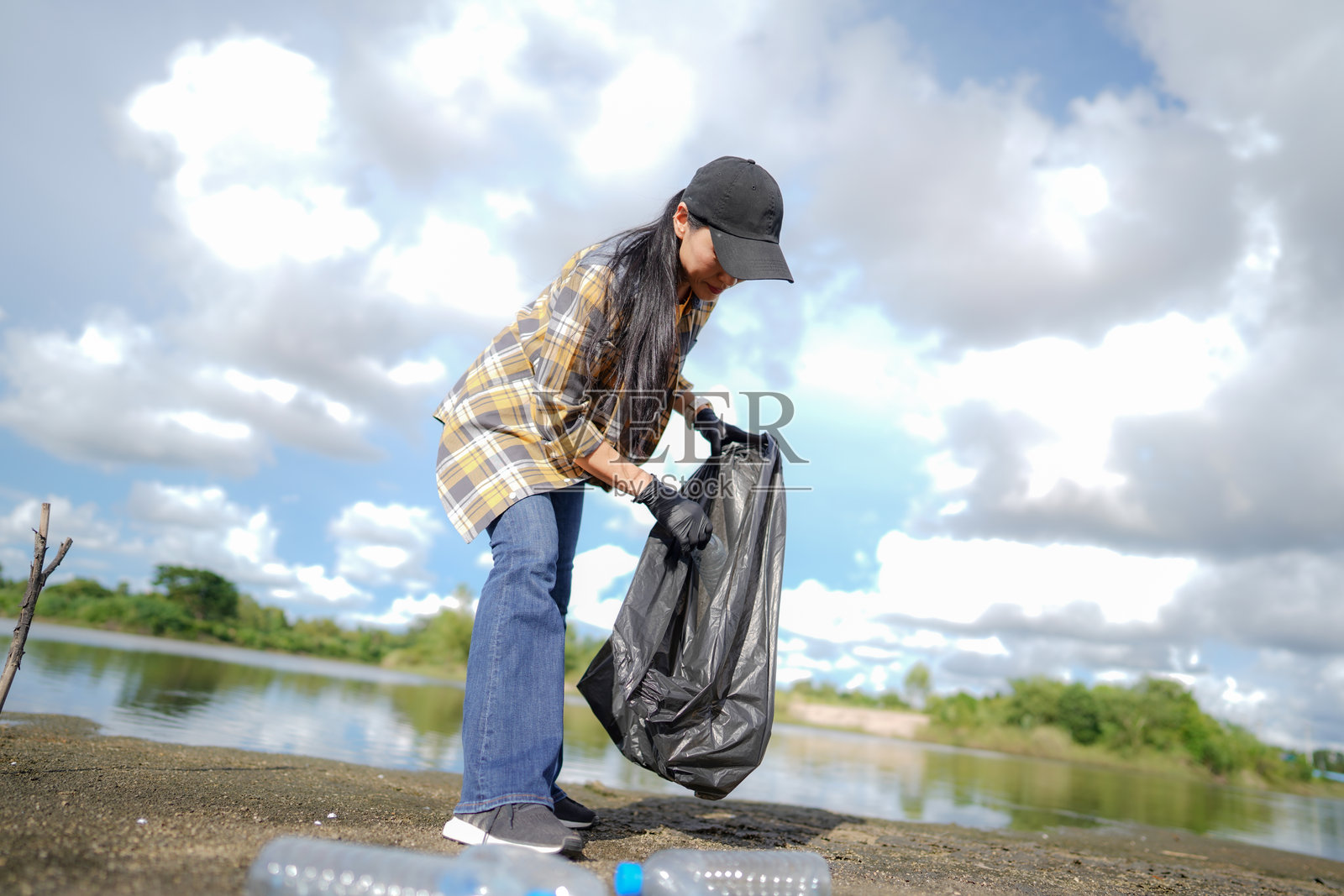 一名妇女在海滩上捡垃圾和塑料水瓶照片摄影图片