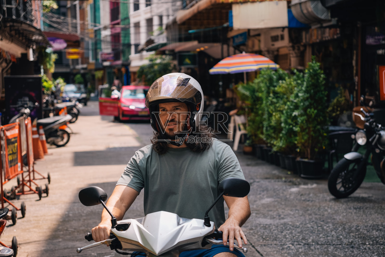 中年男子在东南亚戴露脸头盔驾驶摩托车的横版照片照片摄影图片