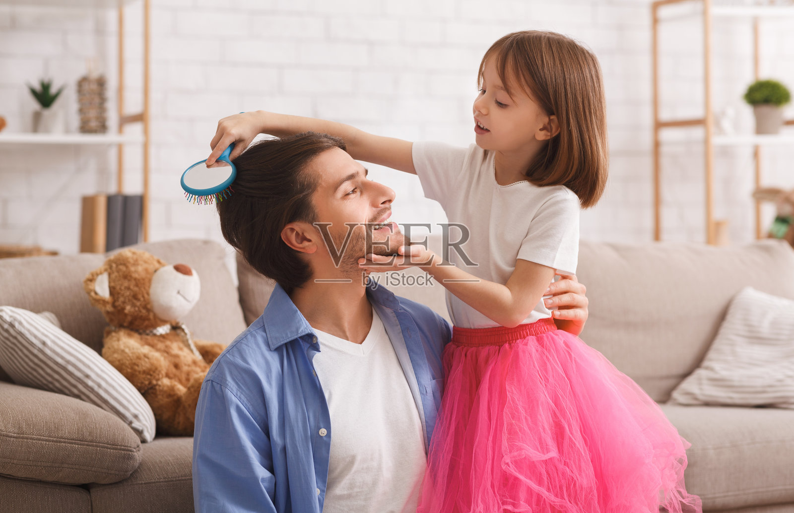 可爱的小女儿在给爸爸梳头发照片摄影图片