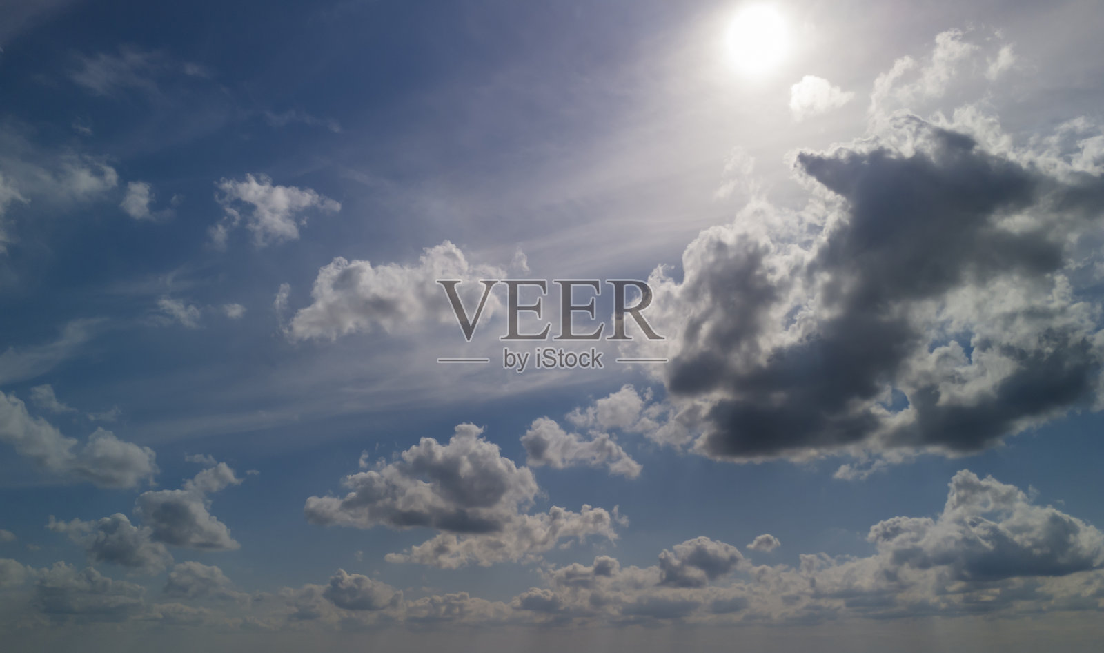 美丽的景色,蓬松的云朵在明亮的蓝天中,阳光普照。非常适合用作背景、自然主题或天气相关的项目。照片摄影图片