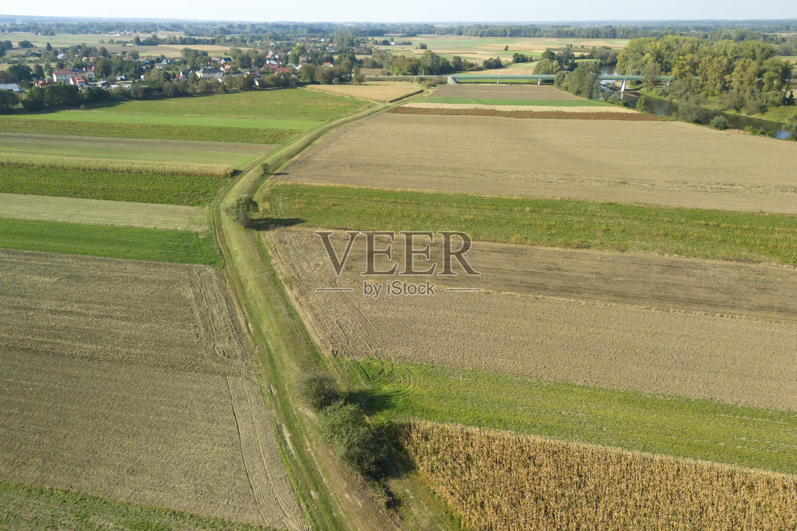 广阔的农业田野鸟瞰图,展示了绿色和棕色的斑块,蜿蜒的小路穿过作物,反映了自然的美丽和乡村的宁静。照片摄影图片