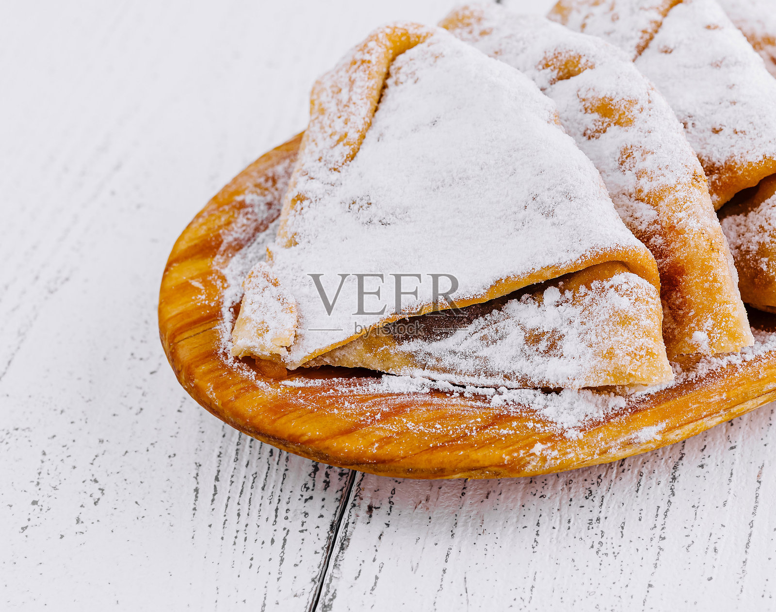 美味的自制煎饼撒上糖粉,放在木盘上。照片摄影图片