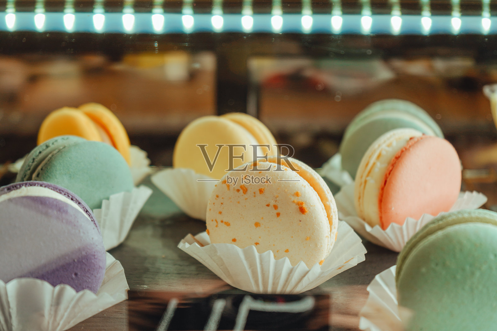 甜点概念。市场上盘子里摆放着不同颜色的马卡龙。法式甜点拼盘。咖啡馆展示柜里的马卡龙。带价格标签的马卡龙蛋糕。照片摄影图片