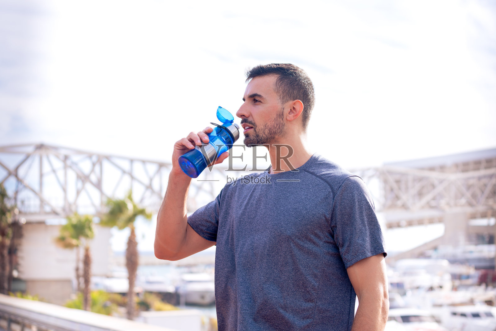 户外运动员从运动水瓶中喝水。照片摄影图片