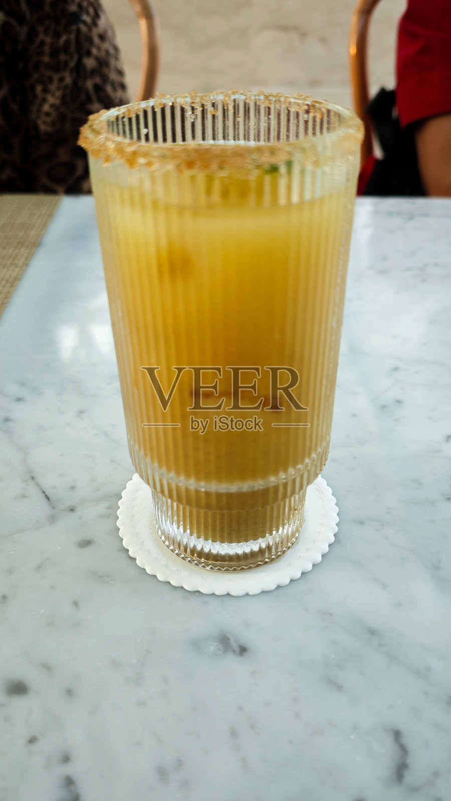 清新的柑橘无酒精鸡尾酒,配有棕糖边缘,放在大理石桌上,上面装饰有青柠片照片摄影图片