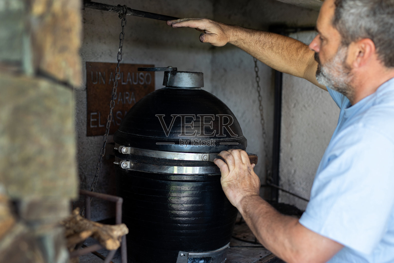 阿根廷男子在烟熏烤架上准备烧烤照片摄影图片