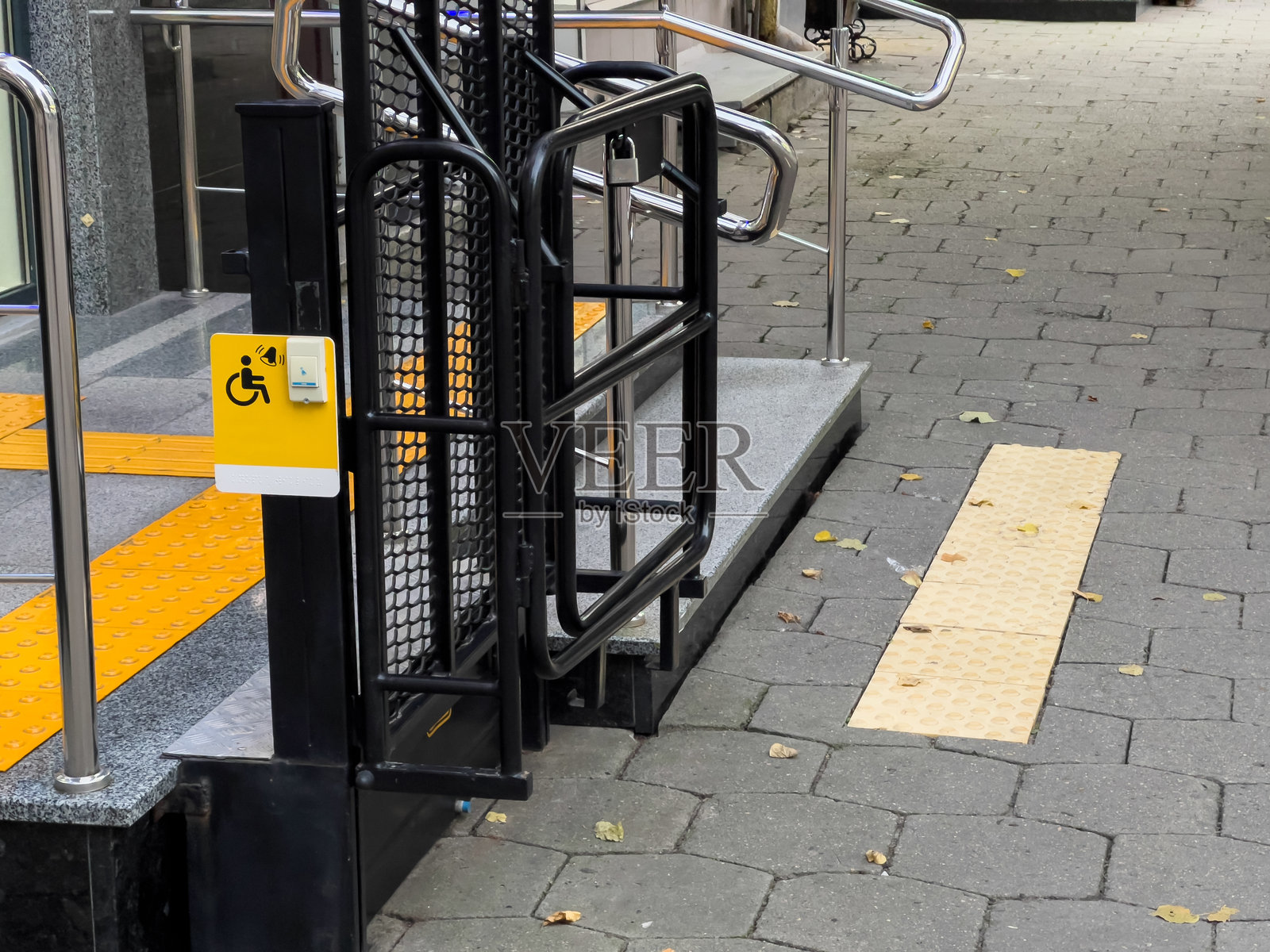 一个带有“无障碍通道”黄色标志的坡道。坡道由金属制成,带有黄黑相间的条纹。照片摄影图片