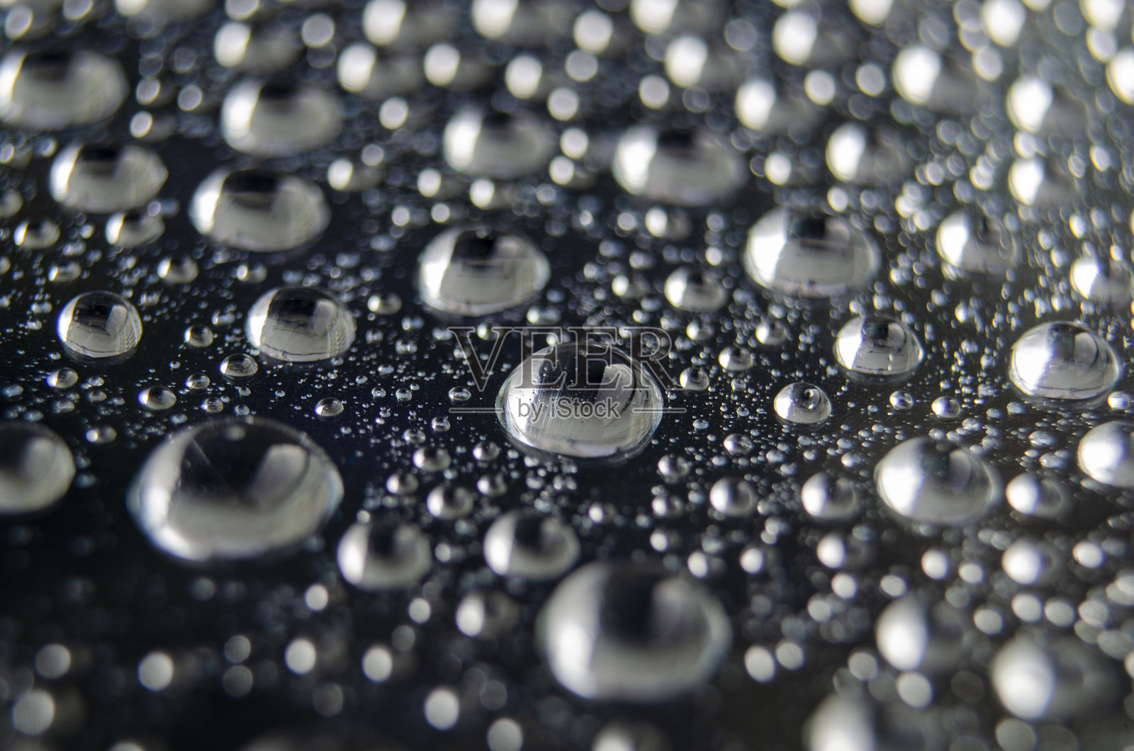 光滑表面上形成图案的雨滴侧视图,清新雨水纹理照片摄影图片