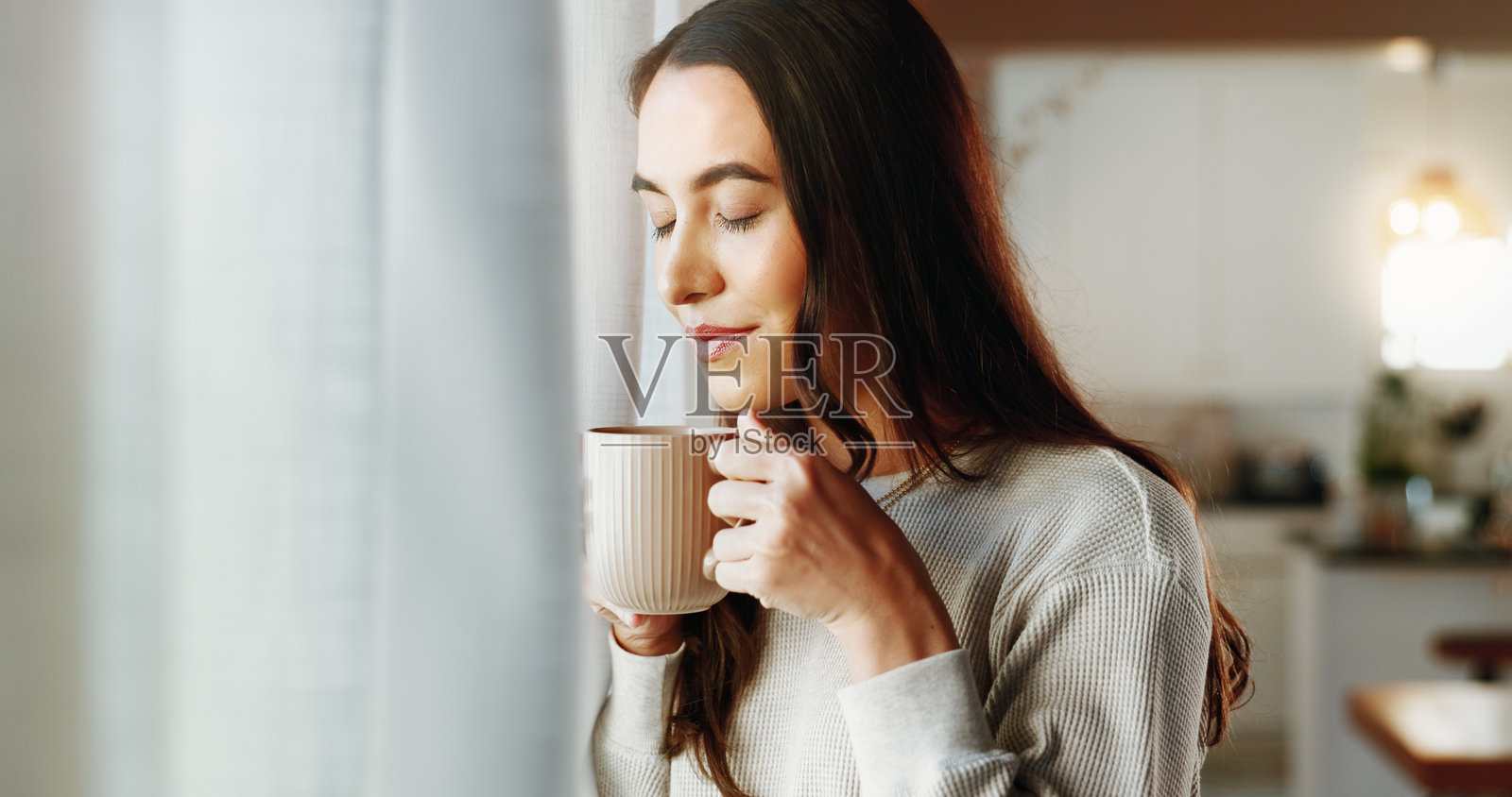 女人在家中享受咖啡的香气与微笑,放松身心,早晨的咖啡因与窗外的气息。女孩在家中喝茶,感受自然的香气,愉快的回忆与放松的时光。照片摄影图片