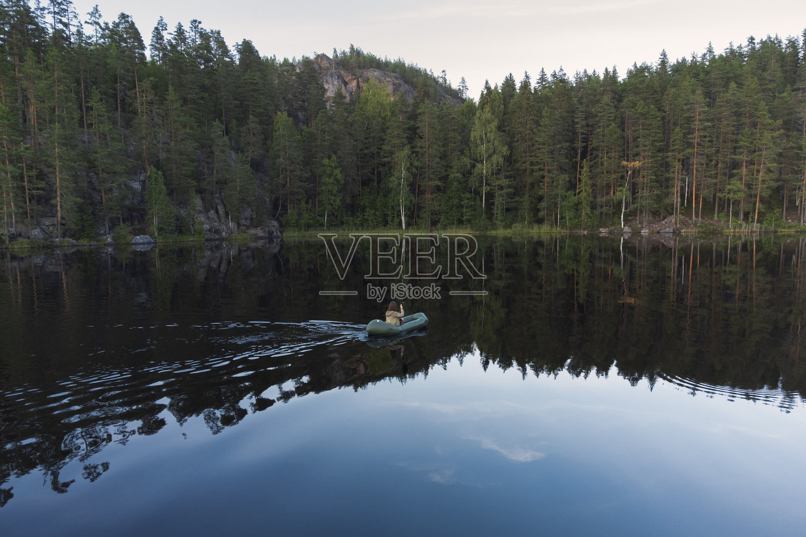 在岩石海岸的森林湖泊上进行充气皮划艇活动照片摄影图片