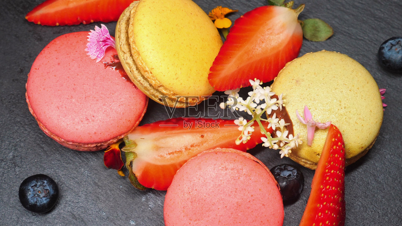 色彩缤纷的法式马卡龙搭配新鲜草莓和蓝莓照片摄影图片