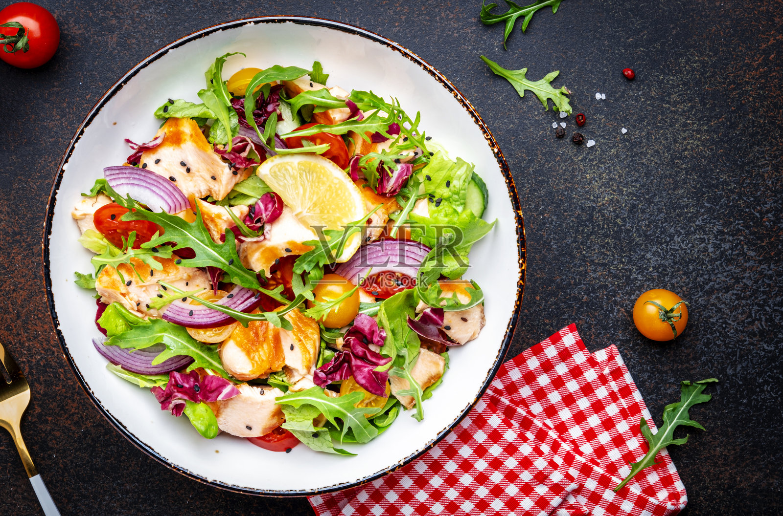 美食爱好者的沙拉,配有烤三文鱼、番茄、黄瓜、芝麻菜、红菊苣、洋葱和生菜,淋上柠檬橄榄油酱。棕色背景,俯视图。照片摄影图片