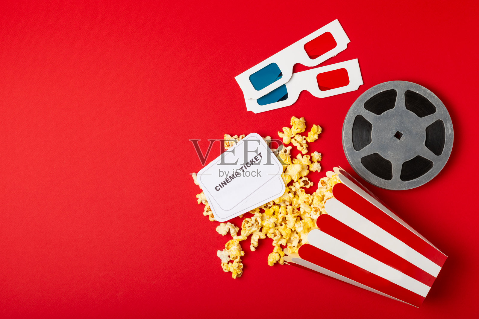 美味的爆米花装在桶里,冰凉的可乐饮料与电影票、电影拍板和3D眼镜一起,背景色彩鲜艳。电影院概念。观看电影。留白处。照片摄影图片
